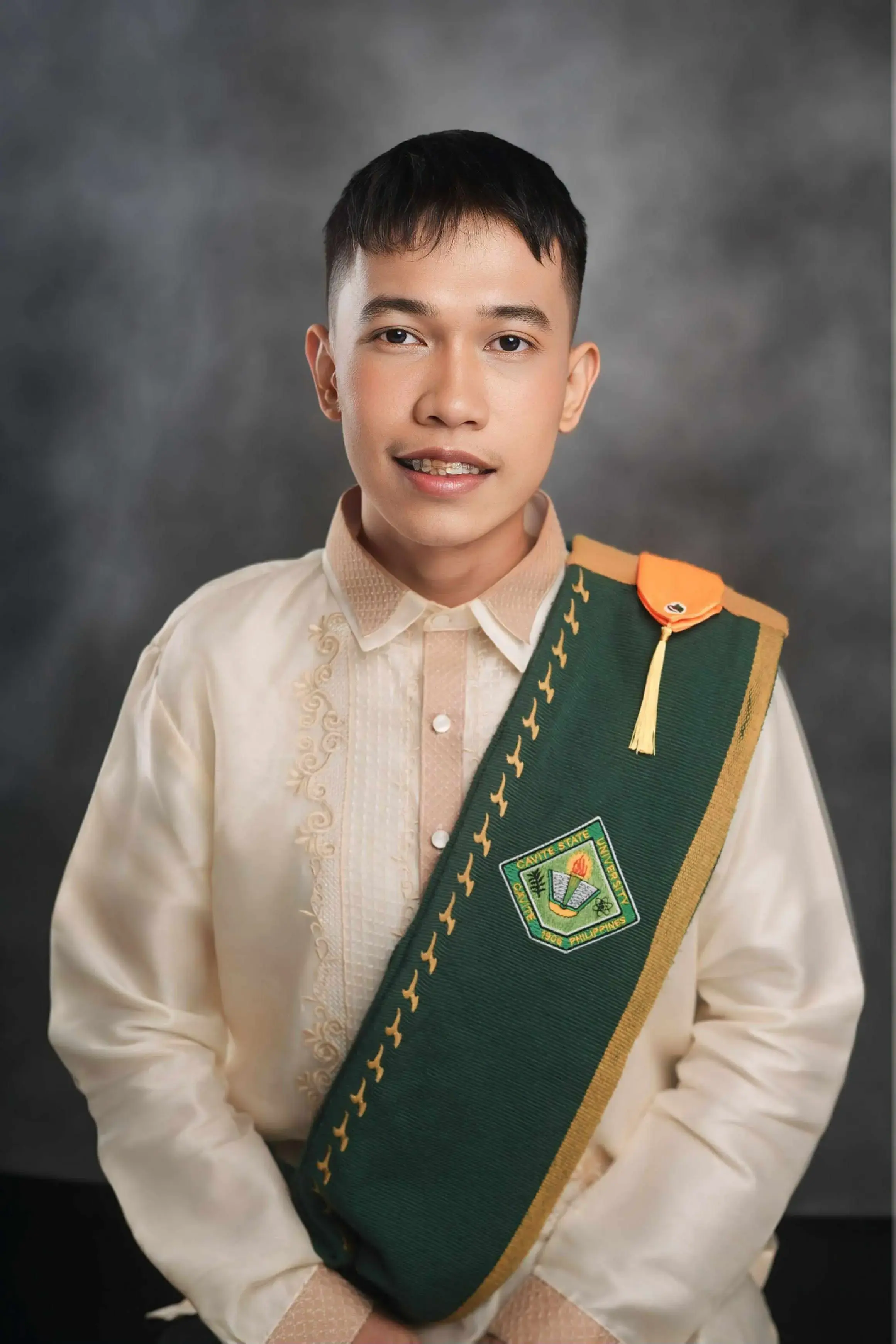 A picture of Darenz Jasper A. Hicap, dressed in a white barong, smiling at the camera with arms crossed.